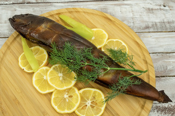 Hot smoked large fish with lemon and sweet pepper on a wooden board