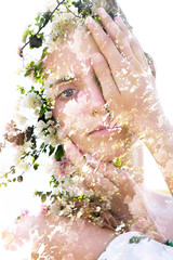 Double exposure portrait of a naturally beautiful woman partially hiding her face combined with stunning pure white flower petals