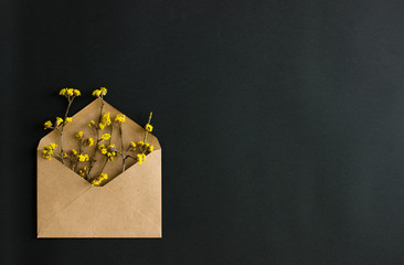 Kraft envelope with yellow flowers on black background. Flat lay. There's room for text or design.