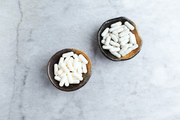 L-Ornithine Amino Acid and Tribulus terrestris extract. Concept for a healthy dietary supplementation. Bright stone background. Top view. Copy space. 