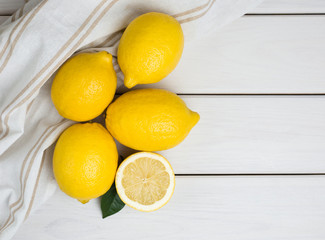 Whole and sliced lemons on white wooden background. Organic fresh citrus fruits, top view, copy space.