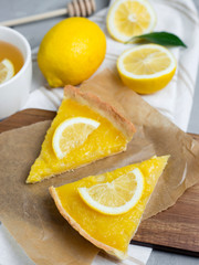 Two pieces of lemon tart with slice of lemons closeup on stone background, top view, copy space.