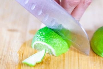 man cuts juicy lime slices on a wooden table, close up, blurry background