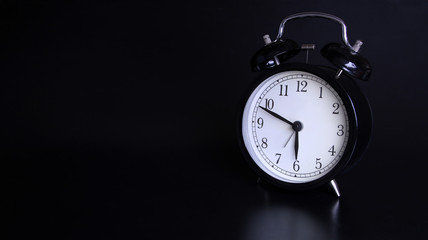 Close up image of old black vintage alarm clock. 10 minutes before six o'clock