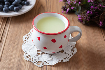 Fresh whey in a mug, with blueberries and flowers