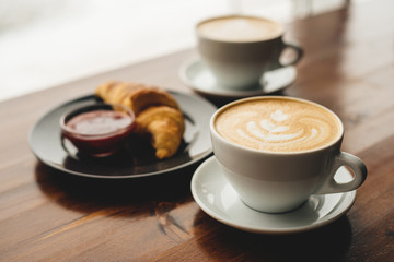 Two cups of cappuccino and croissant