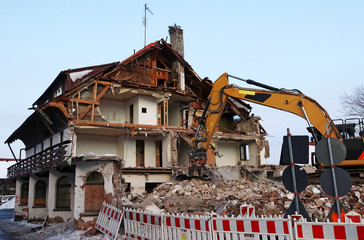 Ein altes marodes Haus wird mit einem Bagger abgerissen