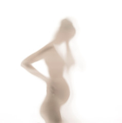 Silhouette of pregnant lady behind the glass wall