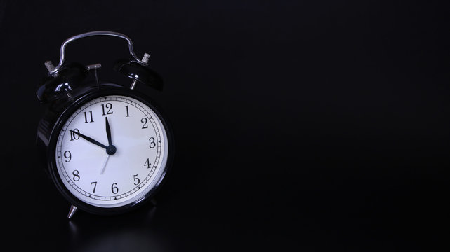 Close up image of old black vintage alarm clock. Ten minutes before twelve o'clock