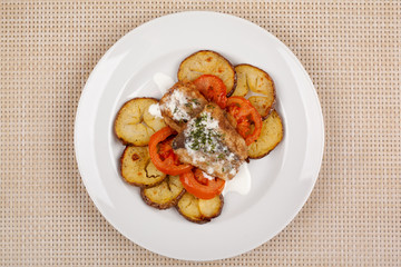 Baked potatoes in the peel sliced with tomato and grilled meat in a white sauce.