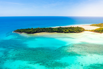 aerial view of an amazing  tropical island covered by trees with turquoise water and yellow sand