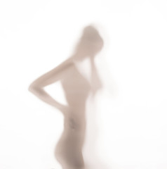 Silhouette of woman dancing behind a glass door