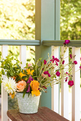 Flowers bouquet in bucket pail on front porch. Simple, country style summer home decor details elements.