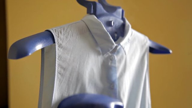 A woman uses steam to iron her blouse. The process of steaming the blouse using a steam cleaner. Close up