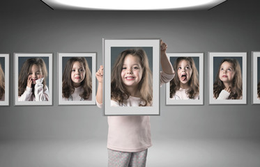 Little girl among lots of her portraits