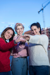 Obraz premium Girls teenagers in summer in the park in the fresh air. Gesture hands show the heart of love. Dressed in casual clothes.