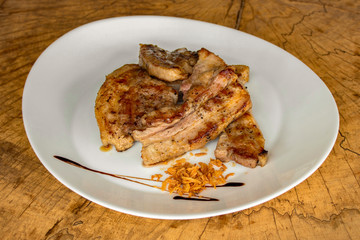 Roasted pork ribs, garnished with onion chips.