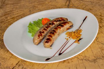 Roasted sausages (specialty of minced meat with spices). Garnished with onion chips, cherry tomato, lettuce leaf and dressing.