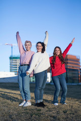 Three happy teen girls friends jumping high in blue sky on summer outdoors background