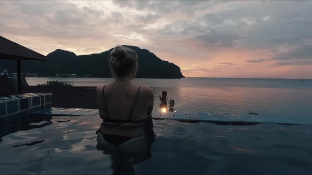 Girl in pool overlooking Koh Pi Pi sunset.