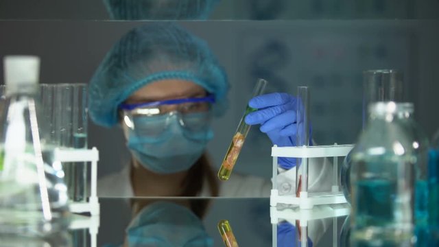 Scientist analyzing meat sample in preservative agent and writing results, food