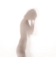 Silhouette of woman dancing behind a glass door