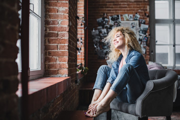 Beautiful blond woman with curly hair relax in a modern loft or home.