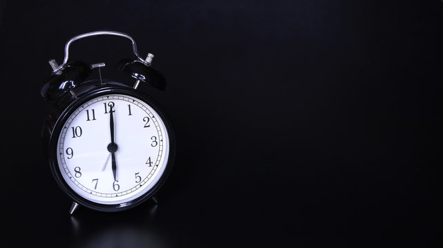 Close up image of old black vintage alarm clock. Six o'clock