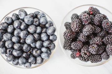 Plates with blueberry and blackberry on a wooden table top view.