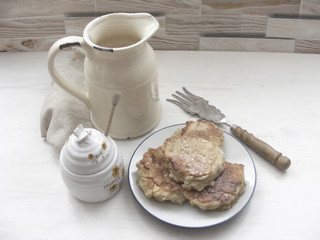 Traditional russian cuisine : pancakes  with oak flakes on  shabby white wooden background with rustic milk jug, silver cultery and honey monochrome photo