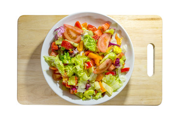 Isolated Healthy vegan food, mix colourful salad with vegetables and fruits on white plate and wooden cutting mat and white background.