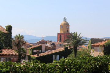 Fototapeta na wymiar View of the tiled roofs and the belfry of the church of Saint-Tropez . Historical streets of Saint-Tropez drowning in greenery.