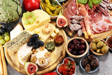 Italian antipasti wine snacks set. Cheese variety, Mediterranean olives, crudo, Prosciutto di Parma, salami and wine in glasses over grunge background.