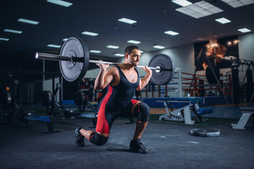 Fototapeta na wymiar Weight lifter doing squats with a barbell in gym