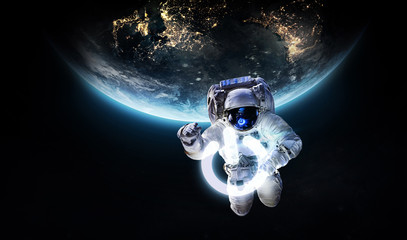 Fototapeta na wymiar Astronaut in outer space with power button. Earth hour event. Planet on the background. Elements of this image furnished by NASA