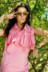 woman posing in sunglasses and rose dress on the jungle background