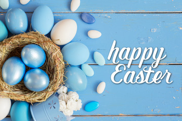 Bright blue colored Easter eggs in nest on wooden background, selective focus image. Happy Easter card 