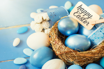 Bright blue colored Easter eggs in nest on wooden background, selective focus image. Happy Easter...