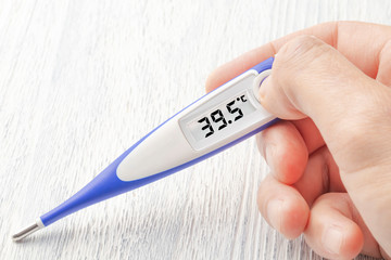 Obraz premium White-blue thermometer with a high temperature of 39.5 degrees Celsius in hand