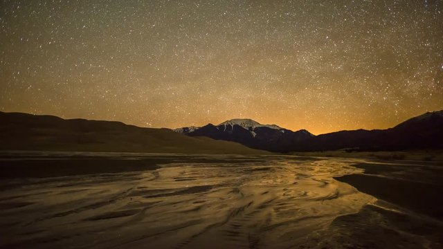 Spring Starry Night at Great Sand Dunes  - Time-lapse of spinning starry night sky over spring Medano Creek, snowcapped peaks, and sand dunes in Great Sand Dunes National Park & Preserve, CO, USA.