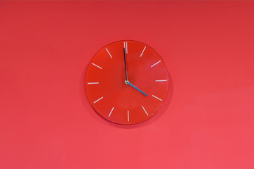 Red round modern analog glass clocks hang on a red wall. Shows the current time 4:00 pm