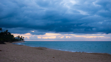 The Caribbean sun setting over the beach at the same time of the arrival of a storm. Rincon, Puerto Rico.