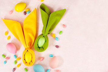 Napkin Easter Bunny, decoration eggs and Easter candy on pink background, copy space