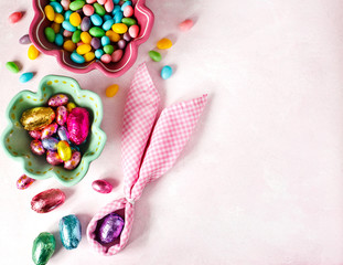 Napkin Easter Bunny, decoration eggs and Easter candy on pink background, copy space