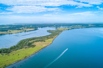 Fototapeta na wymiar Boat sailing on the Manning River leaving water trail - aerial view