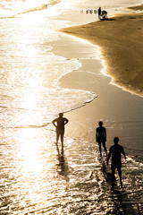 Fototapeta na wymiar Silhouette people playing in the ocean at sunset.