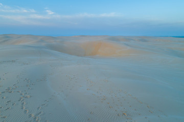 Footprints across sand dunes at dawn - aerial view.