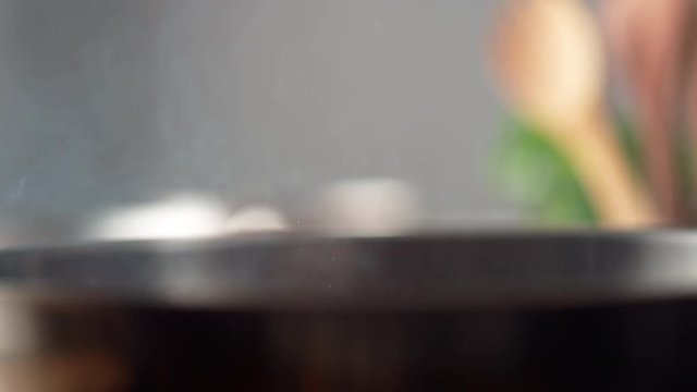 Camera follows adding chopped garlic on cooked bacon in a pan. Shot with high speed camera, phantom flex 4K. Slow Motion.