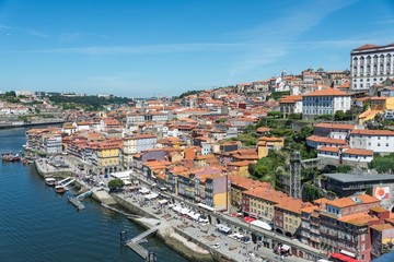 Fototapeta na wymiar A view of Porto and the River Duoro. Photo taken from the Dom Luis bridge. Many buildings are visible with terracotta tiled roofs.