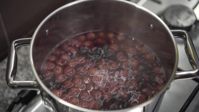 Cooking cherries for soup or kompot in stainless steel pot.